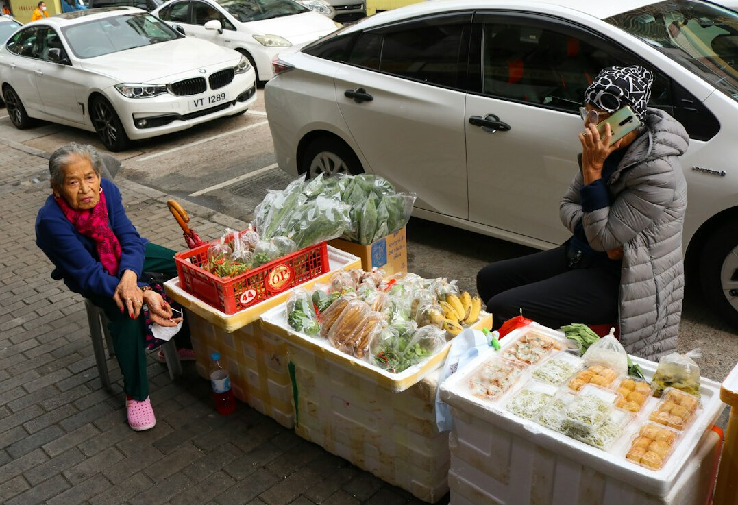 Vendor and customer interacting at an outdoor produce market stall