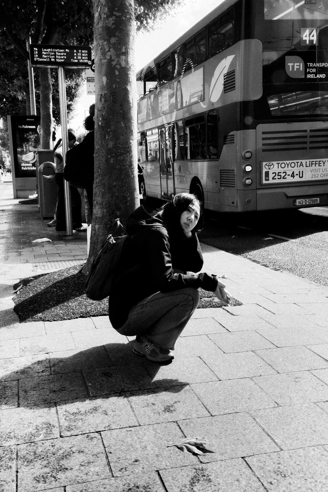 Photographer crouching to take a photo on a city sidewalk
